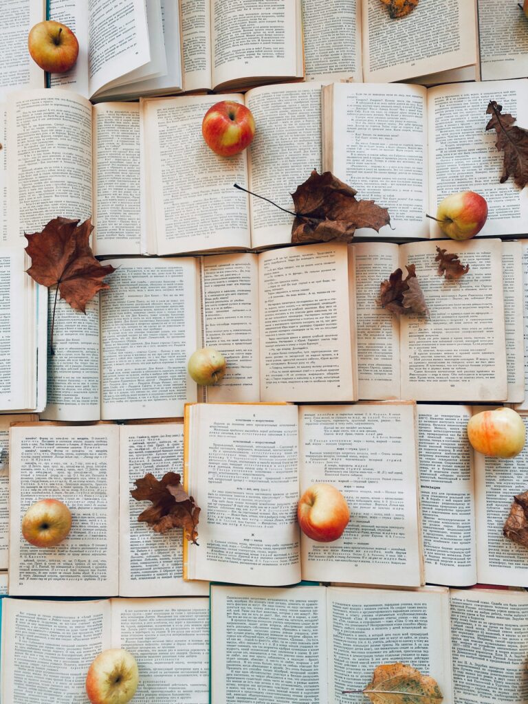 a palette of open books dotted with leaves and apples to illustrate one of many things to do in corvallis - a walking tour called fall into histories