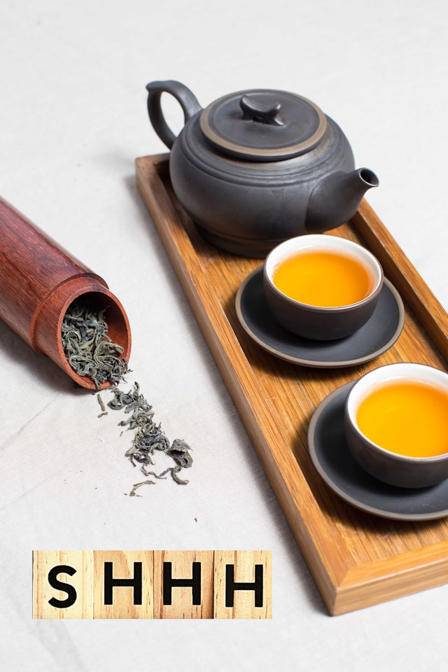a wooden tray with a teapot and two cups of tea, a tube of loose leaf tea shaken out, the letters SHHH to illustrated how we'll spill the tea on these gossip sessions where hearing about the history of downtown corvallis is one of the most fun things to do in corvallis or